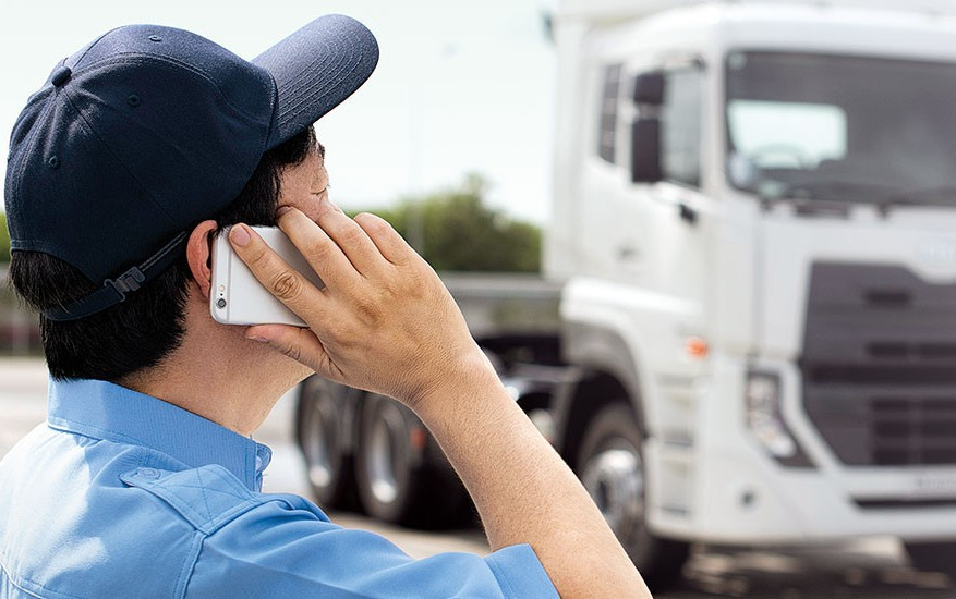 Person in a blue cap talking on the phone near a white truck.