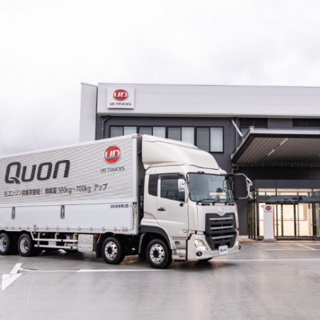 White Quon truck parked in front of a modern industrial building on a cloudy day.