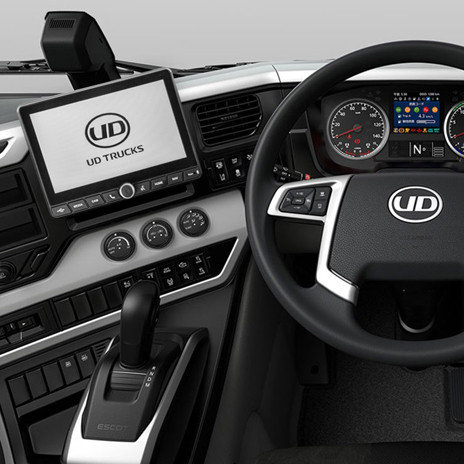 Modern UD Trucks dashboard with steering wheel, digital display, and control panels.