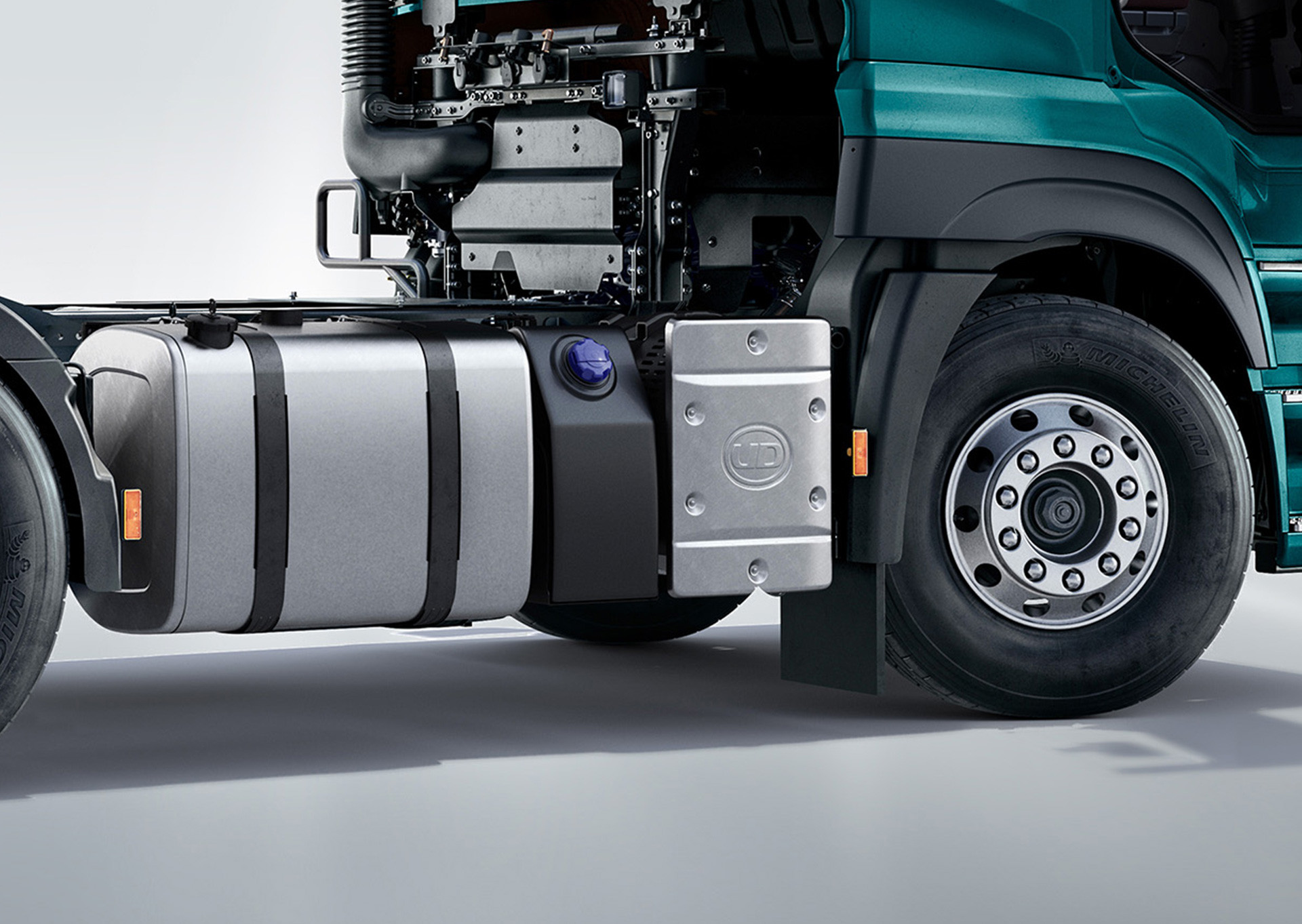 Close-up of a green truck's front wheel and fuel tank, engine partially visible.