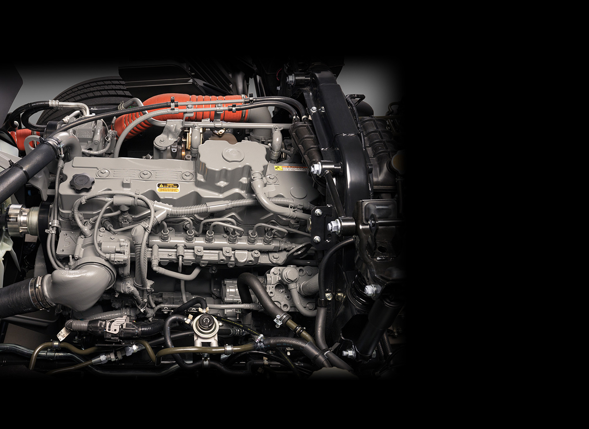 Photograph of a diesel engine with metal pipes and black hoses attached.