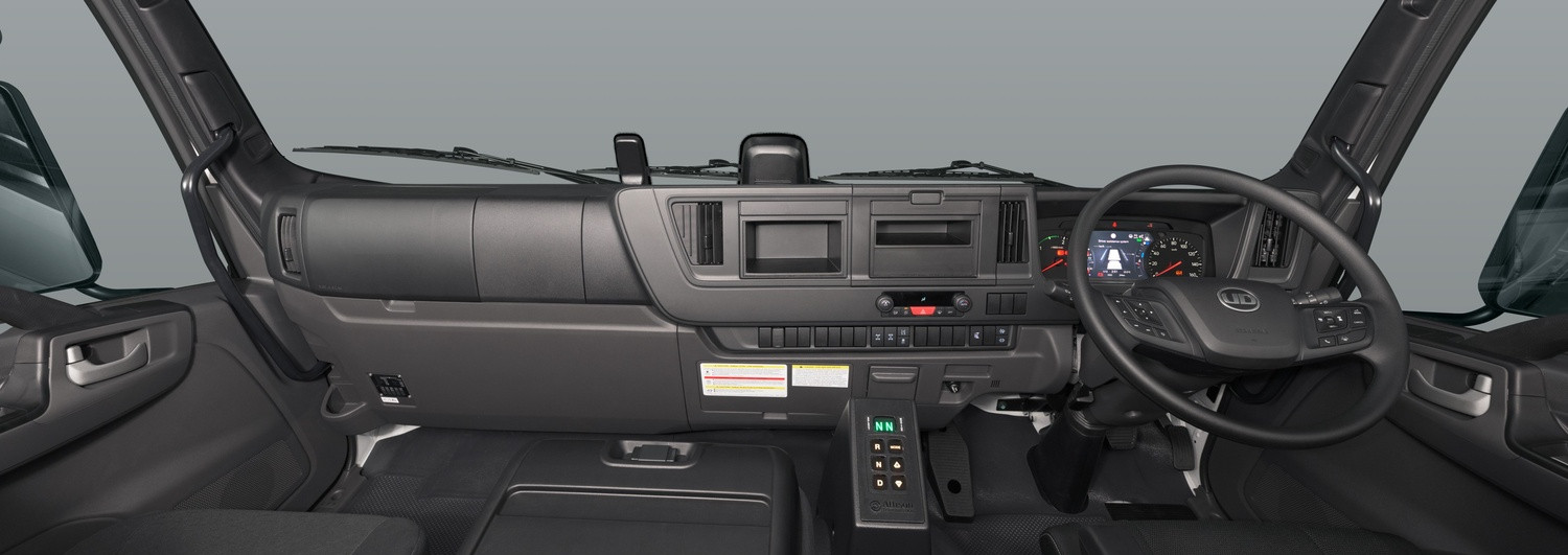 Modern truck cabin interior with dashboard, black seats, and large steering wheel.