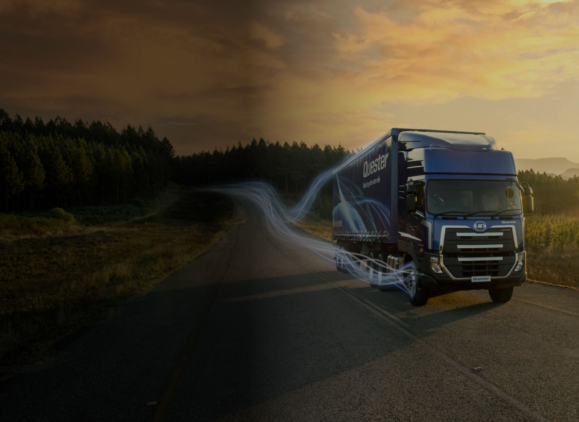 Lori biru di jalan terbuka semasa matahari terbenam, dikelilingi hutan.